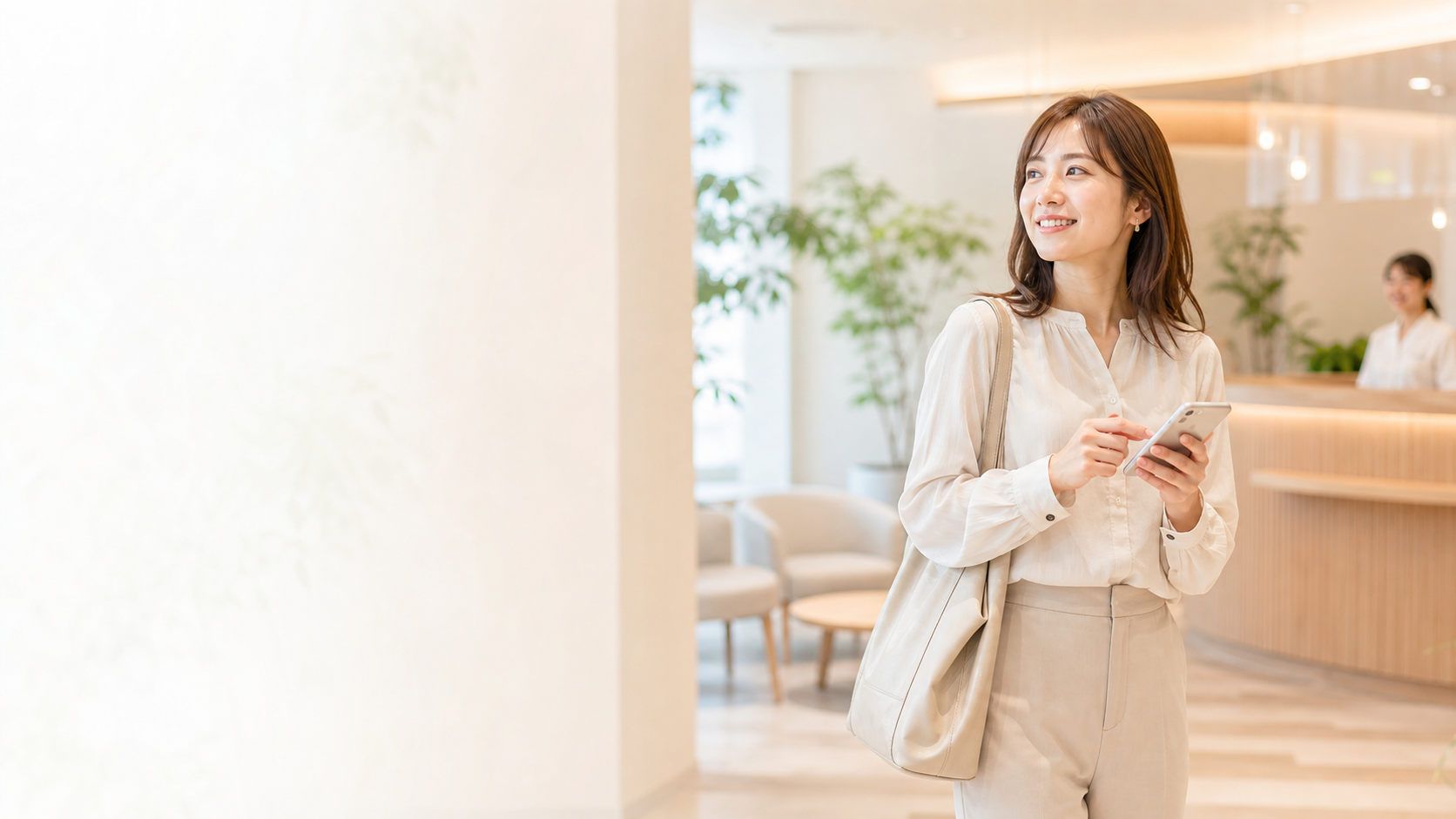 スマートフォンで予約を確認しながら受付を訪れる女性